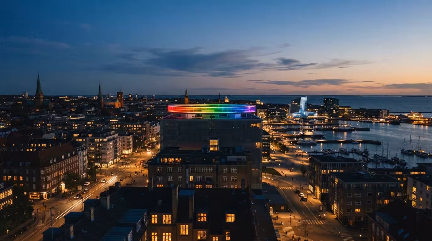 Aarhus havn i skumringen med regnbuen lysende over byens tage