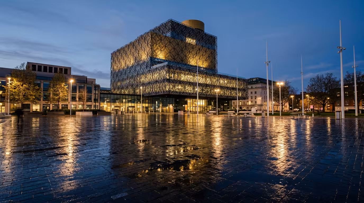 The Library of Birmingham with its filigree facade lit at dusk above Centenary Square